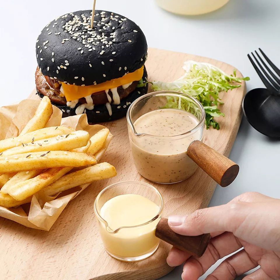 كوب زجاج يد خشب لحليب القهوة والصوصات والعسل علي السفرة ‏